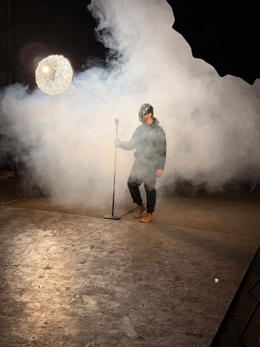 Sänger mit Alienmaske im Nebel am Mikrofonständer