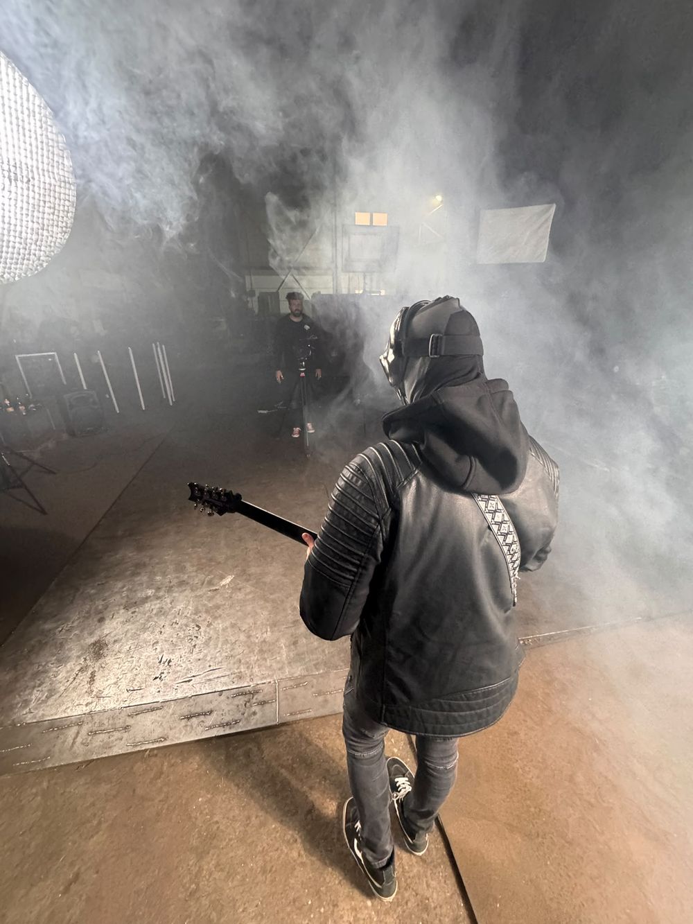 Gitarrist mit Maske von hinten, vor ihm der Kameramann